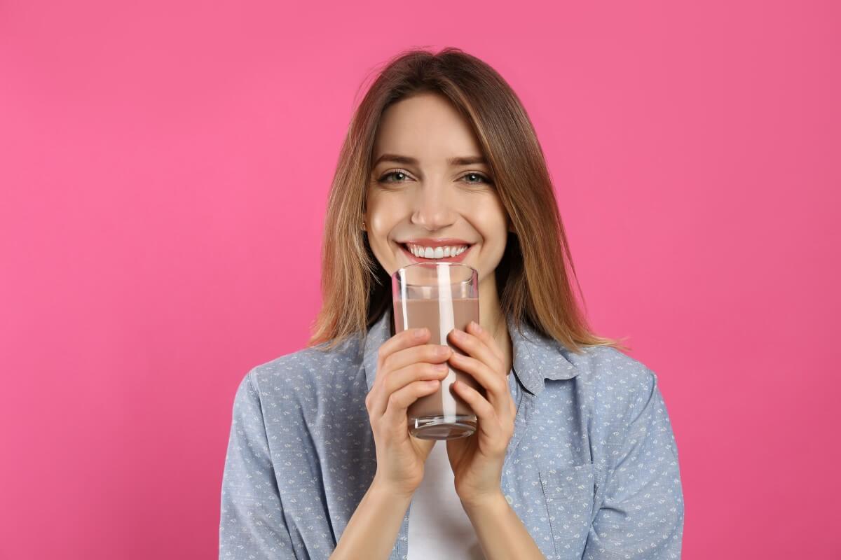 Mlada ženska uživa v beljakovinskem napitku s čokolado