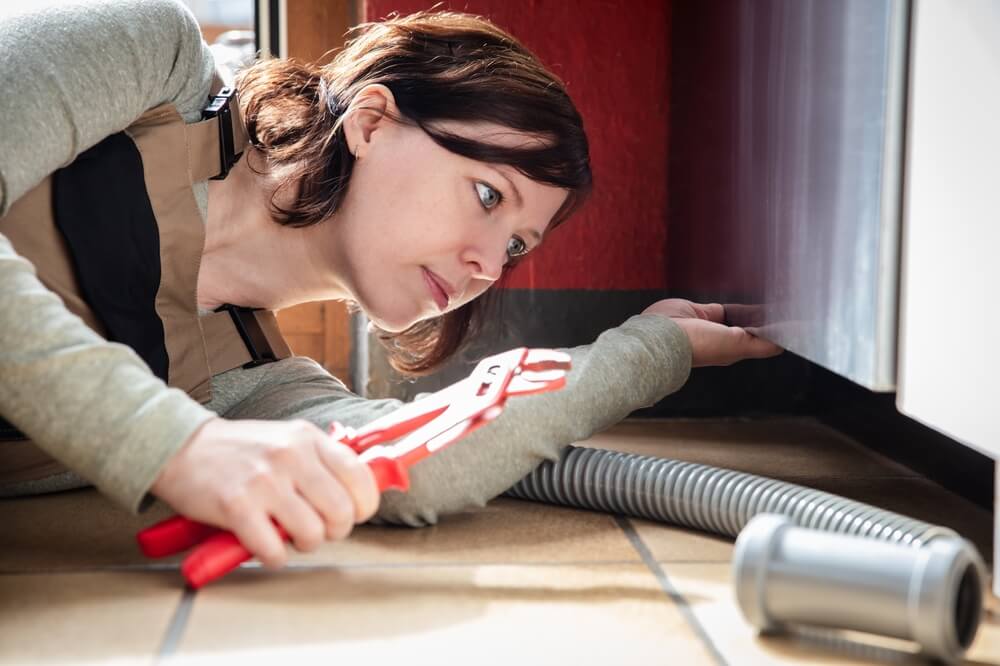 Mlada ženska se sama loteva popravila svojega pomivalnega stroja