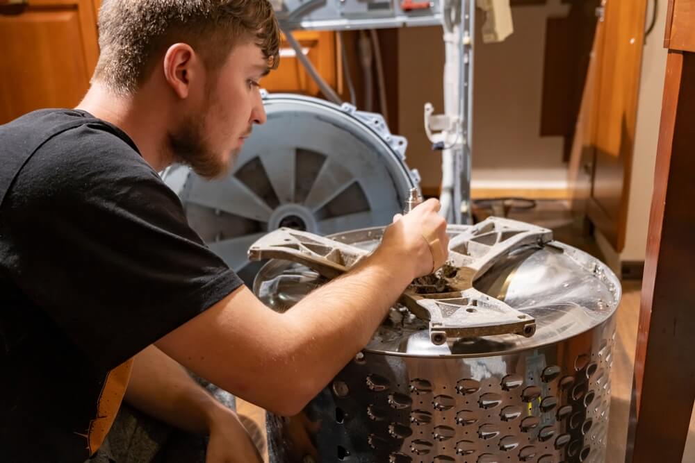 Mladenič sam popravlja svoj pralni stroj