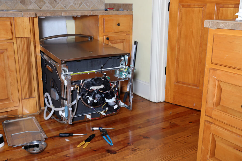 Vgradni pomivalni stroj je izvlečen iz omare, na tleh je orodje, v teku je popravilo